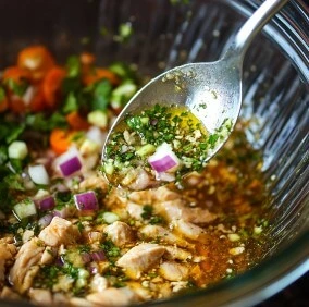 A glass bowl filled with Mexican marinade and fresh ingredients like chopped onions, cilantro, and lime juice.